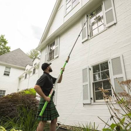 Technician reaching upper-story windows with an extension pole